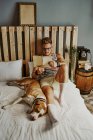 Молодий блондинка читає в ліжку зі своїм собакою. концепція способу життя — стокове фото