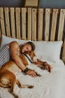 Um jovem loiro dormindo ao lado de seu cachorro na cama. Conceito de estilo de vida — Fotografia de Stock
