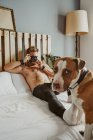 Ein kleiner blonder Junge fotografiert seinen Hund im Bett. Lifestyle-Konzept — Stockfoto
