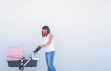 Mother walking with her baby's stroller — Stock Photo