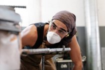 Hombre herrero en máscara protectora en taller haciendo trabajo de metal - foto de stock