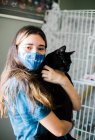 Girl with mask holding cat — Stock Photo