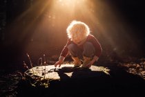 Blond child on tree stump in beautiful forest light in New Zealand — Stock Photo