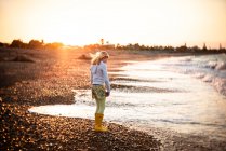 Adolescente em uma praia rochosa na Nova Zelândia ao pôr do sol — Fotografia de Stock