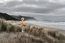 Blond curly haired boy watching the ocean on a cloudy day in New Zealand — Stock Photo