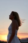 Jovem mulher fecha os olhos enquanto o vento acaricia seu rosto ao pôr do sol — Fotografia de Stock
