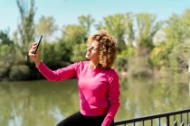 Спортивна жінка використовує свій смартфон, щоб взяти селфі — стокове фото
