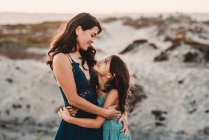 Mãe feliz abraçando 8 anos de idade filha na praia — Fotografia de Stock