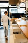 Chef femelle mettant des serviettes sur le comptoir du bar dans un restaurant de cuisine ouverte — Photo de stock