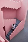 Молодой латинос спускается по лестнице розового здания — стоковое фото