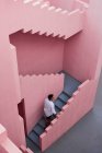 Young latin man goes down the stairs of a pink building — Stock Photo