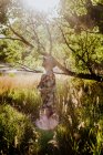 Retrato vertical de uma jovem mulher de pé na floresta olhando para longe — Fotografia de Stock