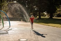 Счастливый ребенок играет в воде в парке — стоковое фото