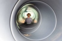 Jovem de cabelos encaracolados criança em um slide tubo em um parque infantil — Fotografia de Stock