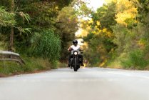Giovane su una moto d'epoca su una strada di montagna al tramonto — Foto stock