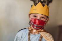 Escuela de niño de edad en vestido como rey con máscara facial - foto de stock