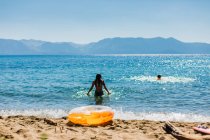 Schwimmen in einem Bergsee mit blauem Himmel und einem orangefarbenen Schlauchboot — Stockfoto
