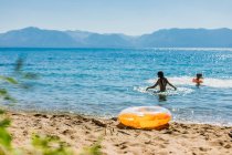 Swimming in a Mountain Lake with Blue Skies and an Orange Inflatable — Stock Photo
