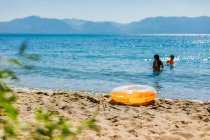 Nadar en un lago azul de montaña con un inflable naranja - foto de stock