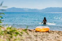 Купаться в лучах солнца на горном озере с надувным — стоковое фото