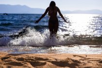 Nadador fica em uma onda com água salpicante em um lago de montanha — Fotografia de Stock