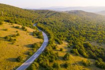 Повітряний вид на порожню дорогу, що перетинає сільську місцевість під час заходу сонця (Хорватія).. — стокове фото