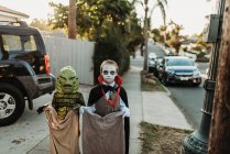 Молодые братья и сёстры, одетые в костюмы на Хэллоуин во время 