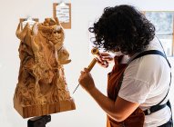 Fille sculpteur travaille avec un couteau et en bois dans le studio — Photo de stock