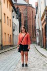 Радостная молодая женщина стоит на улице старого европейского города. Она смотрит в камеру. Концепция путешествия и позитив — стоковое фото