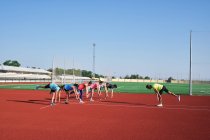 Група жінок практикують передтренування, розтягуючись зі своїм молодим тренером — стокове фото