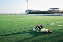 Молодий чоловік відпочиває на траві футбольного поля після тренування — стокове фото