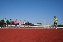 Grupo de mujeres practican pre-entrenamiento estiramiento con su joven traine - foto de stock