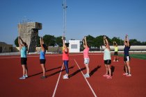 Grupo de mulheres praticam alongamento pré-treino com seus jovens traine — Fotografia de Stock
