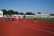 Grupo de mujeres practican pre-entrenamiento estiramiento con su joven traine - foto de stock