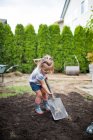Маленькая девочка помогает родителям с проектом на заднем дворе — стоковое фото