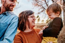 Parents smiling and laughing at young child on a fall evening — Stock Photo