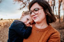 Content toddler hugging his smiling mom outside on an autumn evening — Stock Photo