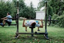 Dos hombres haciendo ejercicio en el jardín en su gimnasio en casa - foto de stock