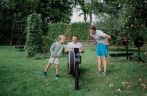 Dos hombres y su hijo haciendo ejercicio en su gimnasio en el jardín - foto de stock