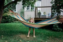 Joven chica de pie junto a una hamaca sonriendo divertirse en un jardín en casa - foto de stock