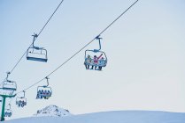 Skieurs sur un télésiège regardant vers le bas avec un fond bleu — Photo de stock