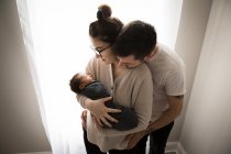 Eltern kuscheln sich ans Fenster und bewundern ihr neugeborenes Baby — Stockfoto