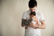 Padre sosteniendo a su hijo contra fondo beige - foto de stock