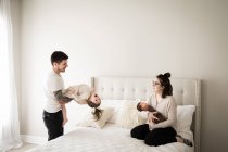 Portrait of happy family sitting on bed, having fun together — Stock Photo