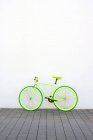 Зелений старовинний міський велосипед з фіксованою передачею на білій стіні — стокове фото