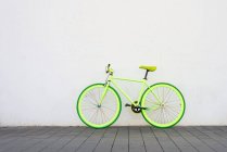 Una bicicleta verde vintage ciudad engranaje fijo en la pared blanca - foto de stock