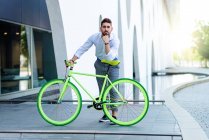 Молодий бородатий чоловік спирається на велосипедне сидіння, дивлячись на камеру — стокове фото