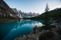 Bellissimo paesaggio di lago di montagna, ragazza seduta sulla roccia — Foto stock