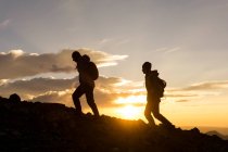 Силует жіночі мандрівники на горі проти неба під час сходу сонця — стокове фото