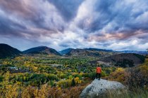 Rear view of male hiker standing on rock against cloudy sky during sunset — Stock Photo